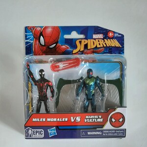 May include: A packaged Marvel Spider-Man toy set featuring Miles Morales and Marvel's Vulture action figures. The figures are in a clear plastic case with a red and white skateboard accessory. The packaging includes the Spider-Man logo and the text "Miles Morales VS Marvel's Vulture".