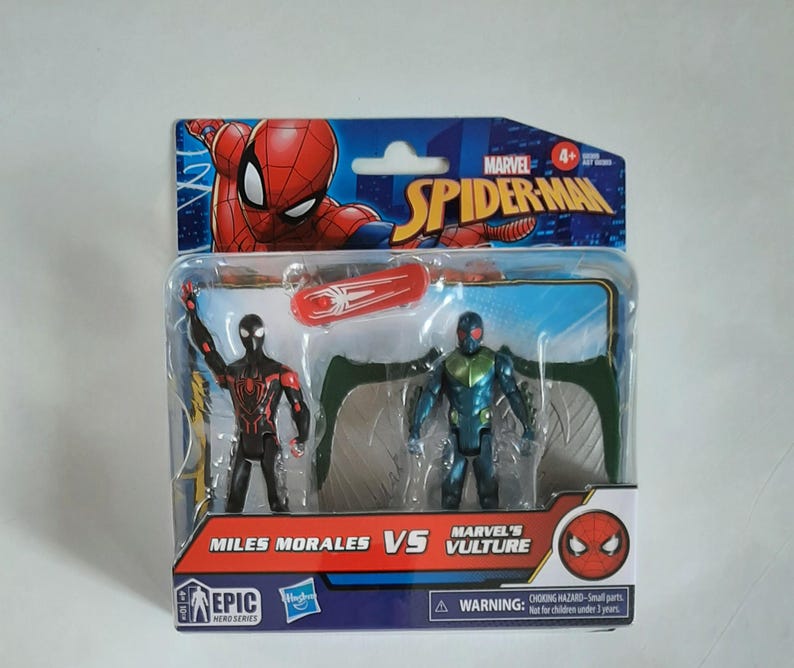 May include: A packaged Marvel Spider-Man toy set featuring Miles Morales and Marvel's Vulture action figures. The figures are in a clear plastic case with a red and white skateboard accessory. The packaging includes the Spider-Man logo and the text "Miles Morales VS Marvel's Vulture".