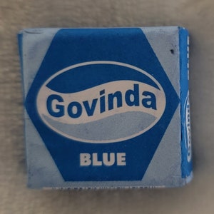 May include: A blue cube with the word "Govinda" in white lettering inside a white oval. The word "BLUE" is printed in white below the oval.