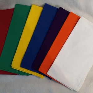 Peut inclure: Une collection de carrés de tissu colorés, rouge, vert, jaune, bleu, violet, orange et blanc. Les carrés sont empilés, présentant un spectre de couleurs. Le tissu semble être de couleur unie, avec une texture lisse.