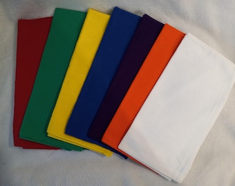 May include: A collection of colorful fabric squares in red, green, yellow, blue, purple, orange, and white. The squares are neatly stacked, showcasing a spectrum of hues. The fabric appears to be a solid color, with a smooth texture.