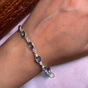 May include: A silver bracelet with a chain and oval-shaped iridescent gemstones. The bracelet has a lobster clasp closure.