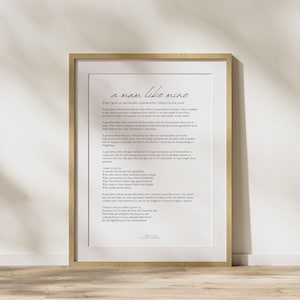 Puede incluir: Una impresión enmarcada con el texto "a man like mine" en un estilo manuscrito. La impresión está en un marco de madera clara y presenta un poema sobre la maternidad. El fondo es de un blanco roto neutro.