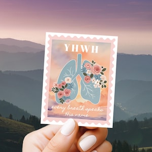 May include: A sticker featuring a light blue illustration of lungs adorned with floral arrangements. The sticker has the text "YWHW" at the top and "every breath speaks this name" at the bottom, set against a pastel background.