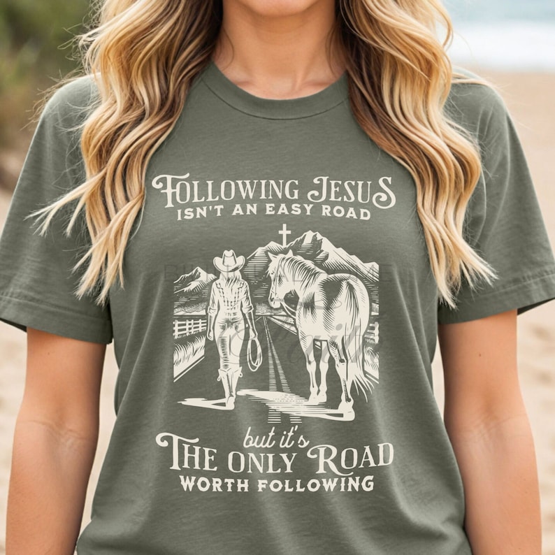 May include: A green t-shirt with a white graphic design. The graphic features a woman on horseback with the text "Following Jesus isn't an easy road, but it's the only road worth following."
