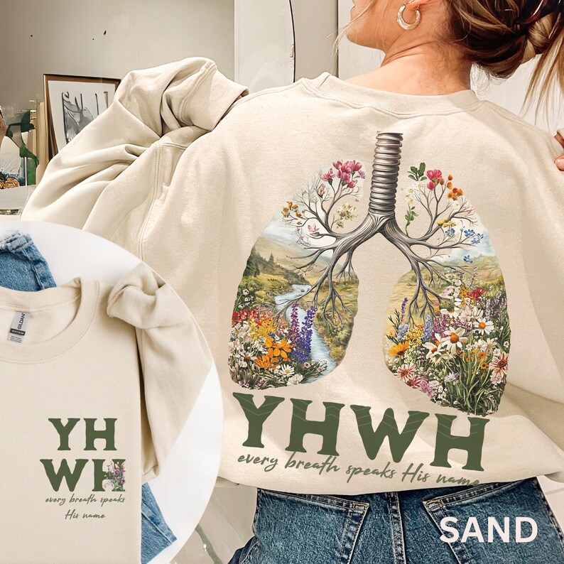 May include: A beige sweatshirt with a floral design of a pair of lungs. The text "YHWY every breath speaks His name" is printed on the front of the sweatshirt.