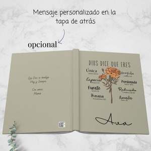 May include: A beige book with a floral design on the cover. The book has the text "Dios dice que eres" and a list of words with bible verses. The words are "unica", "especial", "fuerte", "preciosa", "escogida", "perdonada", "redimida", and "amada". The book also has the text "Ava" written on the cover.