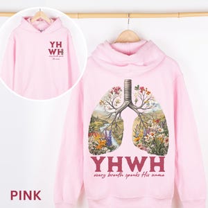 May include: Pink hoodie with a floral lung design and the text "YHWY every breath speaks His name".