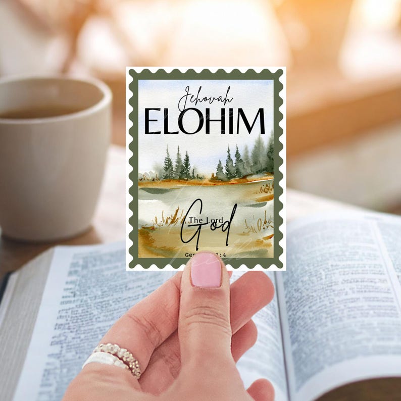 May include: A rectangular sticker with a watercolor landscape scene, featuring a lake and trees, and the words "Jehovah ELOHIM" and "The Lord God" in elegant script. The sticker has a green border and is held over an open book.