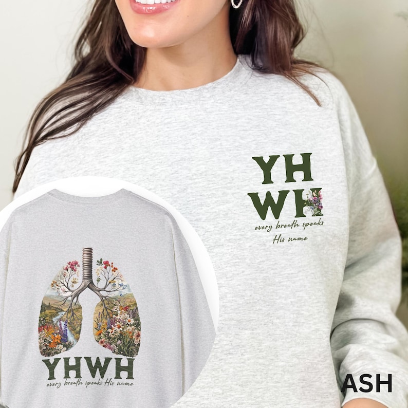 May include: A gray sweatshirt with a floral design on the front and the words "YHWH every breath speaks His name" on the back. The sweatshirt also has the words "YHWH" on the front.