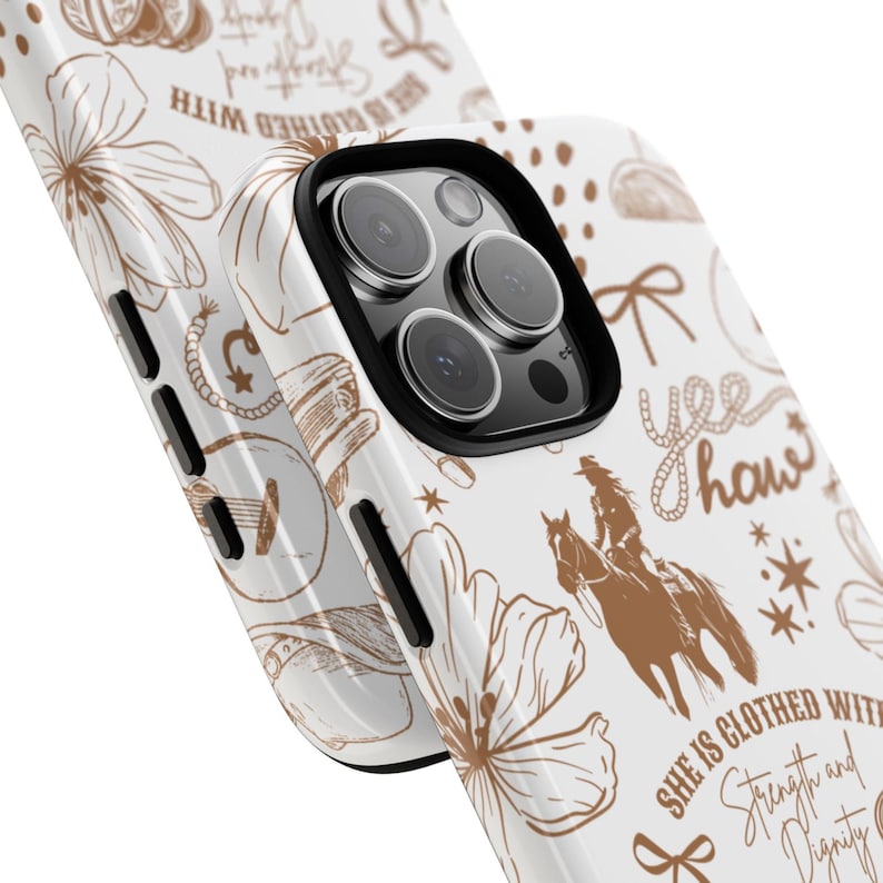 May include: White phone case with a brown and white design. The design features a floral pattern, a cowboy riding a horse, stars, and the text "She is clothed with strength and dignity." and "Yee Haw".