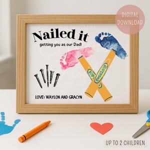 May include: A framed print with the text "Nailed it getting you as our Dad!" features pink and blue footprints as hammers, with screws and the words "SUPERDAD" on the hammers. The bottom reads "LOVE: WAYLON AND GRACYN".