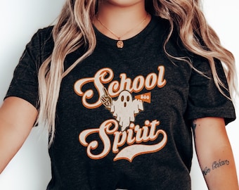May include: A heather black t-shirt with a vintage-style graphic of a ghost holding a sign that says "Boo" and the text "School Spirit".