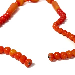 May include: A broken orange and yellow beaded necklace with a metal clasp. The necklace is made of round and oval beads.