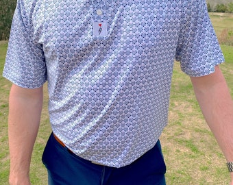 Pode incluir: Uma camisa polo branca de manga curta com um padrão geométrico azul e branco. A camisa tem um colarinho abotoado e um pequeno logotipo no peito esquerdo.