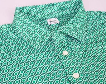 Peut inclure: Un polo à manches courtes vert et blanc à motif géométrique avec un petit logo sur le côté gauche de la poitrine. Le logo est rouge et blanc et représente un drapeau et la lettre "H".