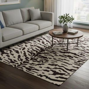 May include: A living room with a light grey sofa, a round wooden coffee table, and a rug with a zebra stripe pattern in cream and dark brown. The room has hardwood flooring and a large window.