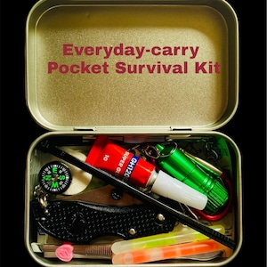 May include: An open, rectangular metal tin labeled "Everyday-carry Pocket Survival Kit" contains a small compass, a folding knife, a tube of red glue, a green flashlight, and other survival tools. The kit is designed for portability.
