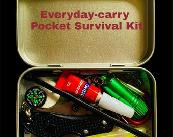 Könnte beinhalten: Geöffnete rechteckige Metallbox mit der Aufschrift "Everyday-carry Pocket Survival Kit". Enthält einen Kompass, ein Klappmesser, roten Kleber, eine grüne Taschenlampe und weitere Survival-Werkzeuge. Kompaktes Survival-Kit.