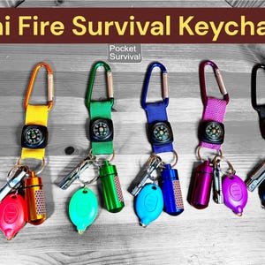 May include: Mini Fire Survival Keychains in various colours. Each keychain includes a compass, a carabiner clip, and a small survival kit with a fire starter and other tools. The keychains are red, yellow, green, blue, purple, and black.