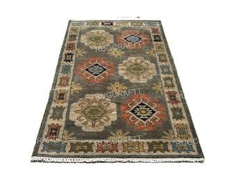 May include: A rectangular area rug with a dark gray background featuring repeating geometric medallions in shades of orange, beige, and blue. The border displays a series of smaller, colorful patterned squares, and the short ends have white fringe.