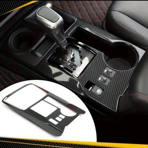 Pode incluir: Kit de guarnição interior de carro em fibra de carbono preta com um porta-copos e um contorno de alavanca de mudanças. O kit inclui uma peça separada para a área do console central.