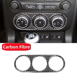 May include: A black carbon fiber trim kit for a car dashboard. The trim kit has three round openings for gauges or controls. The text "Carbon Fibre" is printed in red on a white background.