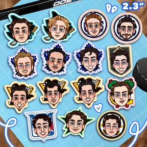 Könnte beinhalten: Eine Sammlung von vierzehn runden und geformten Vinyl-Aufklebern mit illustrierten Porträts von Eishockeyspielern. Jeder Aufkleber zeigt einen einzigartigen Gesichtsausdruck vor verschiedenen teambezogenen Hintergründen. Der Text 2,3" ist sichtbar.