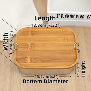 May include: A rectangular bamboo lunch box with a stainless steel rim and two metal clasps. The lunch box measures 7.32 inches long, 5.52 inches wide, and 2.28 inches high. The bottom diameter is 6.2 inches.