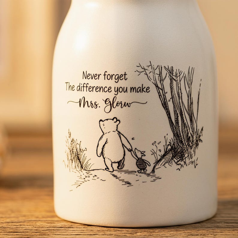 May include: White ceramic vase with a black illustration of a bear and a smaller animal walking together. The vase has the text "Never forget the difference you make Mrs. Glory."