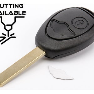 Può includere: Una chiave per auto nera con una lama dorata e un solo pulsante. La chiave è su uno sfondo bianco. Il testo "CUTTING AVAILABLE" è nell'angolo in alto a sinistra dell'immagine.
