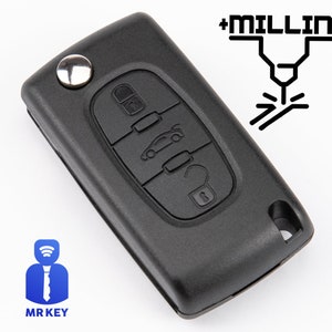 May include: Black car key fob with buttons for locking, unlocking, and opening the trunk. The key has a silver button and a hole for a key ring. The image includes the text "+MILLING" and the "MR KEY" logo.