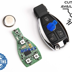 Könnte beinhalten: Eine grüne Leiterplatte mit vier Knöpfen und ein silberner Schlüsselanhänger mit vier Knöpfen, darunter ein Schloss-, Entriegelungs- und Kofferraumknopf. Der Schlüsselanhänger hat einen blauen Knopf mit einem Schlüssels symbol und dem Text "CUTTING AVAILABLE". Das Bild enthält auch eine silberne Batterie und einen blau-weißen Garantiesticker mit der Aufschrift "6 MONTHS WARRANTY".
