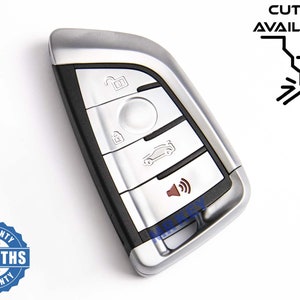 Peut inclure: Une clé de voiture argentée et noire avec plusieurs boutons, dont un cadenas, un déverrouillage et une icône de voiture. La clé a une finition métallique et le texte "CUTTING AVAILABLE" est visible. Le logo "MR KEY" est également présent.