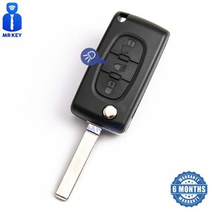 May include: Black car key with four buttons and a silver key blade. The buttons have icons for unlocking, locking, trunk release, and headlights. The key has a 6 month warranty.