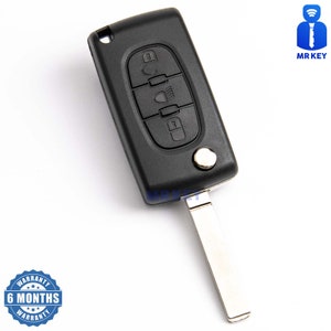 May include: Black car key with four buttons and a silver key blade. The buttons are labeled with icons for unlock, trunk, and lock. The key has a 6-month warranty.