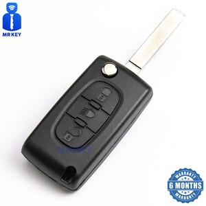 May include: Black car key fob with four buttons. The buttons are labeled with icons for unlock, lock, trunk, and headlights. The key fob has a silver metal key blade attached.
