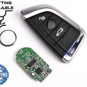 Könnte beinhalten: Ein Autoschlüssel mit silberner Zierleiste und schwarzen Knöpfen, zusammen mit einer Leiterplatte, einer Batterie und dem Text "CUTTING AVAILABLE". Das Bild enthält auch den Text "6 MONTHS WARRANTY".