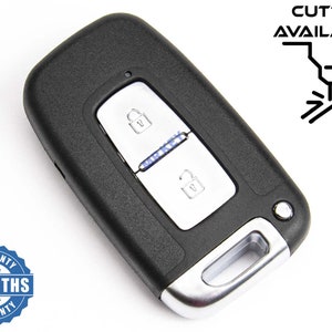 Peut inclure: Clé de voiture noire avec deux boutons, l'un pour verrouiller et l'autre pour déverrouiller. Le porte-clés a une garniture argentée et un petit voyant LED. Le porte-clés est sur un fond blanc.  "CUTTING AVAILABLE" est écrit en noir sur fond blanc.  Un autocollant de garantie avec le texte "6 MONTHS WARRANTY" est dans le coin inférieur gauche de l'image.
