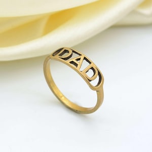 Op de afbeelding: Gouden ring met het woord "DAD" uitgesneden in de band.