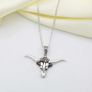May include: A silver chain necklace with a detailed bull head pendant.
