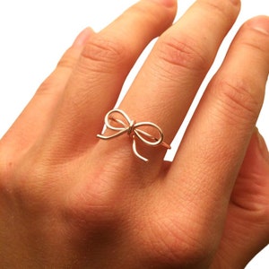Puede incluir: Un anillo de color dorado con un diseño de lazo.