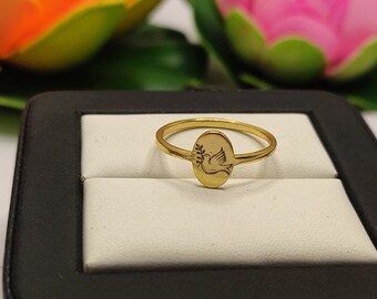 May include: A gold ring with a dove and olive branch design. The ring is in a black ring box with a white interior.