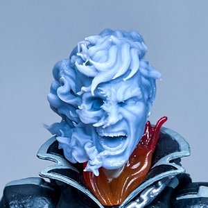 Może przedstawiać: Niebieska i biała figurka akcji postaci z czaszką na twarzy i łańcuchem na klatce piersiowej. Figurka ma na sobie czarną skórzaną kurtkę z czerwonym szalikiem.