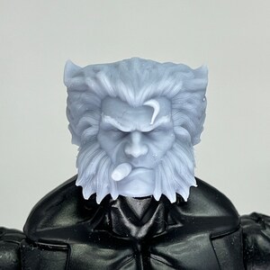 May include: A close-up of a grey plastic action figure head with a white beard and moustache. The figure has a furrowed brow and a cigarette in its mouth.