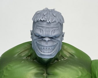 May include: A green Hulk action figure with a grey, detailed head sculpt. The figure is wearing brown trousers.