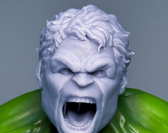 May include: A close-up of a 3D printed model of the Hulk's head. The model is painted in a light grey colour and has a detailed facial expression, including a wide open mouth and furrowed brows.
