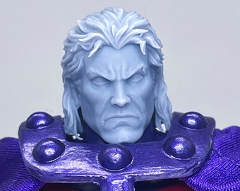 May include: A close-up of a superhero action figure's head. The figure has a white, sculpted head with a stern expression. The figure is wearing a purple cape and a metal chest piece with a magnetic design.