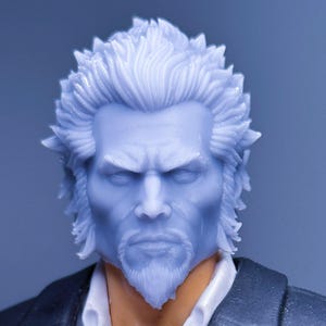 May include: A detailed close-up of a figurine's head and upper body. The figure has light blue hair and a matching beard, with a stern expression. It wears a black suit jacket over a white collared shirt.