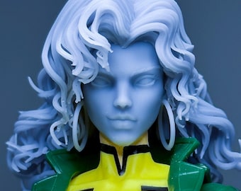 May include: A detailed action figure of Rogue from the X-Men. The figure features a blue-skinned face with white hair, large hoop earrings, a yellow bodysuit, and a green jacket. The figure has a black collar and a symbol on the chest.